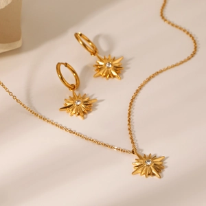 Macro detail of 18K gold plated stainless steel starburst necklace and earrings with zircons