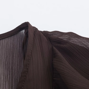 Detail of coffee brown pleated chiffon dress showing soft fabric texture and shoulder seams