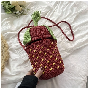 Macro view of strawberry shaped woven bag with detailed red texture and green leaves