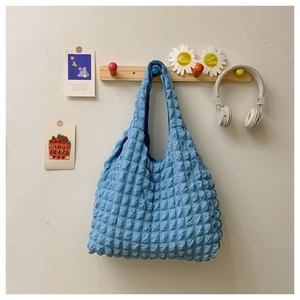Blue waffle texture tote bag hanging on a hook in a cozy, minimalist lifestyle setting
