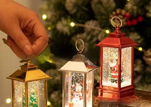 Close-up of three festive Christmas lanterns with Santa, snowman and tree figurines