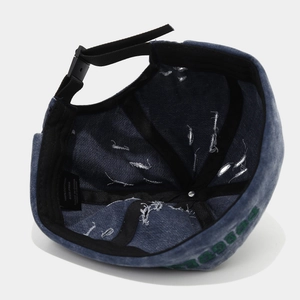 Dettaglio del berretto in denim blu con etichetta 100% cotone e cinturino regolabile