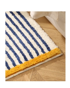 Detailed close-up of blue and white striped plush bathroom mat on wooden floor