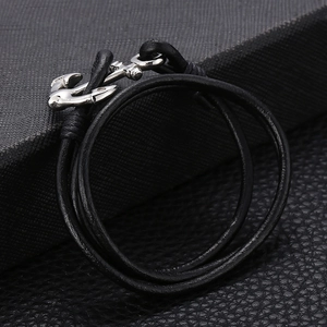 Macro shot of silver anchor clasp on multi-layer black braided leather nautical bracelet
