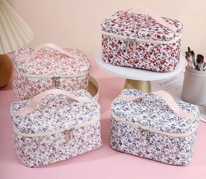 Detailed view of four floral cosmetic bags in red, pink, and blue with pink handles