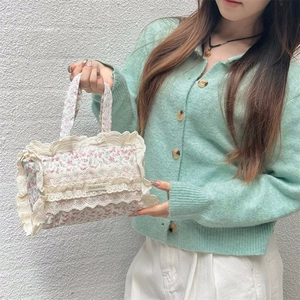 Détail du sac cabas en toile florale avec bordures en dentelle beige et étiquette