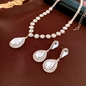 Détail d'une parure de bijoux goutte de luxe avec collier et boucles sur soie