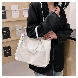 Dettaglio borsa tote bianca in ecopelle con tasca anteriore indossata con un abito nero