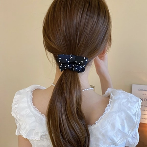 Close-up of black and white polka dot hair scrunchie with bow tie on ponytail