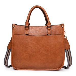 Sac fourre-tout marron en similicuir avec poignée et bandoulière rayée sur fond blanc