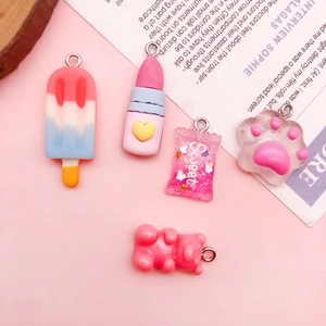 Macro detail of five pink resin DIY charms including ice pop, lipstick, and gummy bear shapes