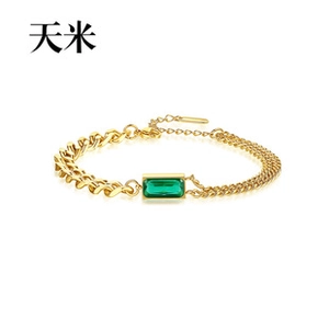 Detail of gold chain bracelet featuring a green emerald-cut zircon and asymmetric links