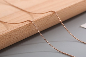 Macro view of thin rose gold snake bone chain showing its smooth woven metal texture