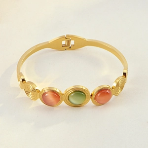 Detail of bohemian gold stainless steel bracelet with orange and green cat eye stones