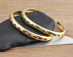 Macro view of 18k gold plated cuffs with green and pink marquise zircon crystals