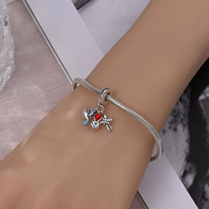 Close-up of silver charm bracelet with Peace dove and red heart on wrist