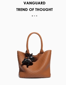 Detail of a brown woven leather tote bag with a black French Bulldog pendant accessory