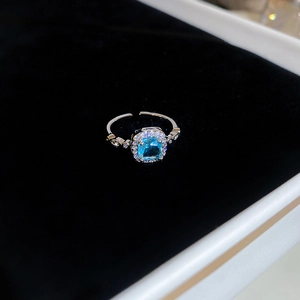 Macro view of blue square gemstone ring in silver setting with sparkling side stones