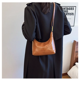 Detailed view of the brown leather shoulder bag with embossed brand logo on smooth texture