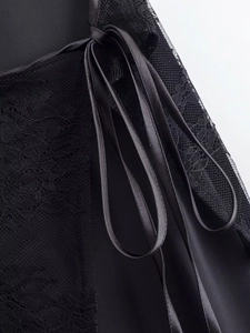 Close-up of elegant black lace texture and shiny satin ribbon on these women's trousers
