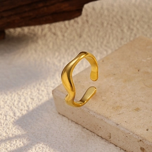 Macro shot of 18K gold plated stainless steel wave ring on a textured stone base