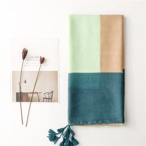 Detail view of tri-color geometric linen scarf with tassels and soft mint fabric texture