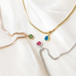 Three elegant pendant necklaces in gold, rose gold and silver on white silk