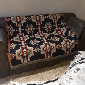 Close-up of bohemian woven picnic blanket with tribal patterns and decorative fringe