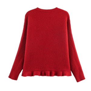 Detail of red knit sweater featuring a ribbed texture and wavy ruffled hemline