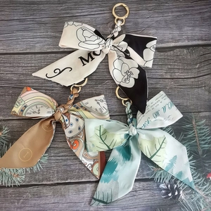 Macro view of silk camellia bow keychains with vintage clock and leaf patterns