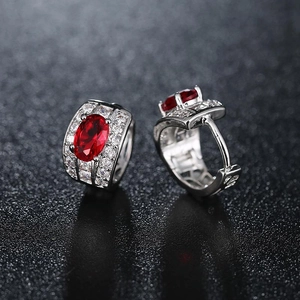 Silver hoop earrings with a red oval gemstone surrounded by sparkling crystals on black back