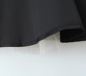 Détail de l'ourlet en satin noir avec doublure en tulle blanc sur une robe courte