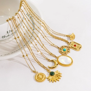 Gold stainless steel necklaces with natural stone pendants on a white ceramic plate