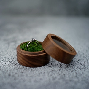 Detail of round walnut wood jewelry box with green moss lining and silver diamond ring
