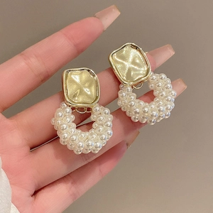 Gros plan du clou carré doré vintage avec détail de la boucle en perles pendantes