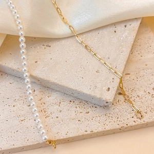 Détail du collier moitié perles et chaîne à maillons dorés sur surface en pierre