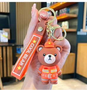 Detail of firefighter bear keychain with orange silicone strap and gold metal clasp