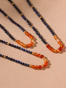 Détail de perles de lapis-lazuli et agate rouge sur chaîne en acier doré 18k
