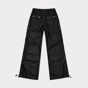 Detailed view of black wide-leg cargo pants with tactical pockets and glossy finish