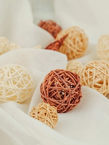 Macro shot of natural woven rattan balls in beige and brown colors on white fabric
