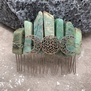 Macro detail of handmade natural crystal hair comb with silver crescent moon on mossy rock