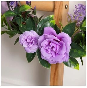 Close-up of purple artificial rose wreath with silk flowers on a natural vine base