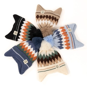 Detailed view of five colorful knitted beanies with cat ears and pom-pom decorations