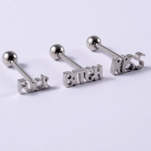 Macro shot of stainless steel 14G tongue rings with engraved punk style letter designs