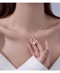Close-up of a gold V-shaped pendant necklace with pavé zircons worn on model's neck