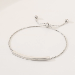 Macro detail of adjustable stainless steel bracelet featuring 'LOVER DREAM' engraving
