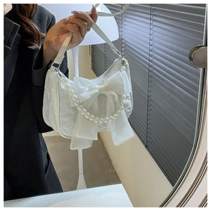 Detail of white jacquard hobo bag with organza bow and pearl chain decoration