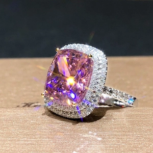Macro shot of cushion cut pink zircon ring with dual halo setting on a textured display box