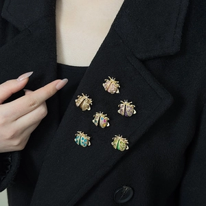 Set of six colorful rhinestone beetle brooches shown on a model's black jacket