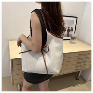 Detail of herringbone canvas tote bag with brown leather trim and side drawstring detail